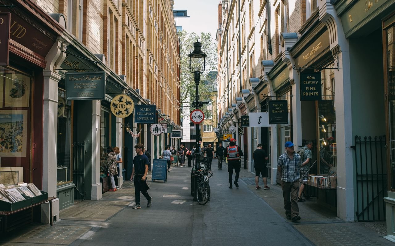 Lively London street scene with people shopping in a narrow alley filled with antique shops.