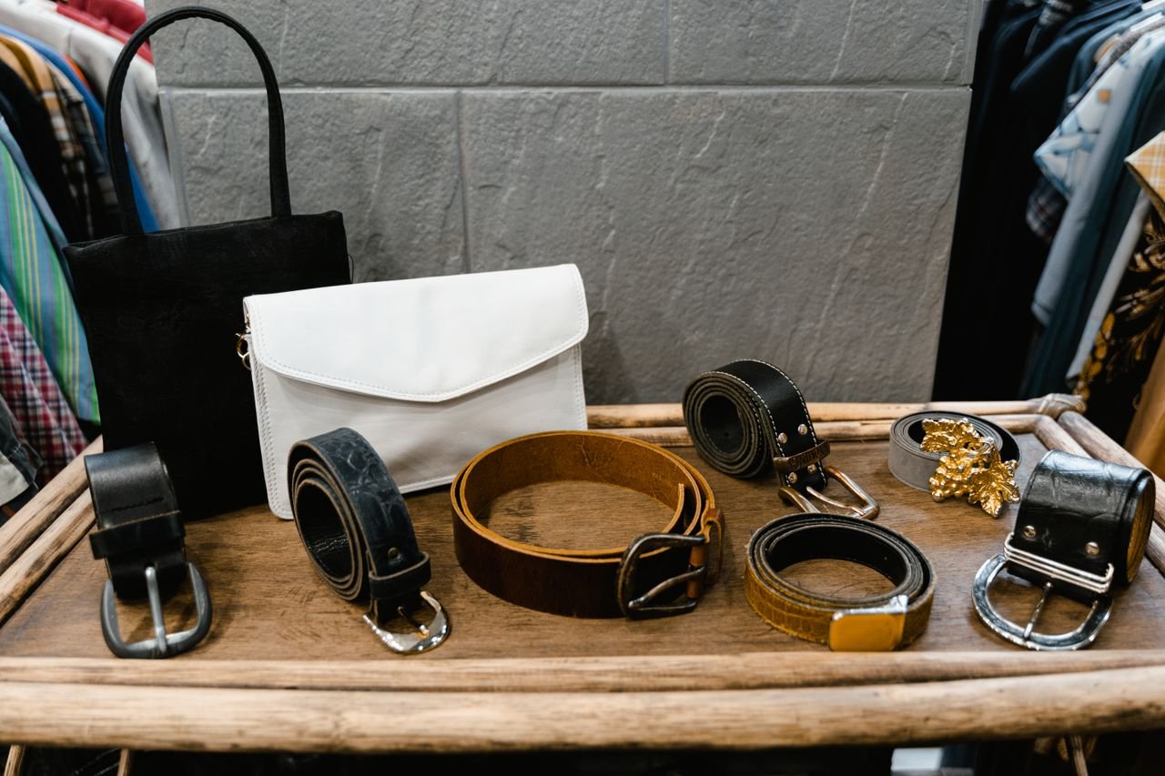 A collection of stylish belts and handbags displayed on a wooden rack in a fashion boutique.